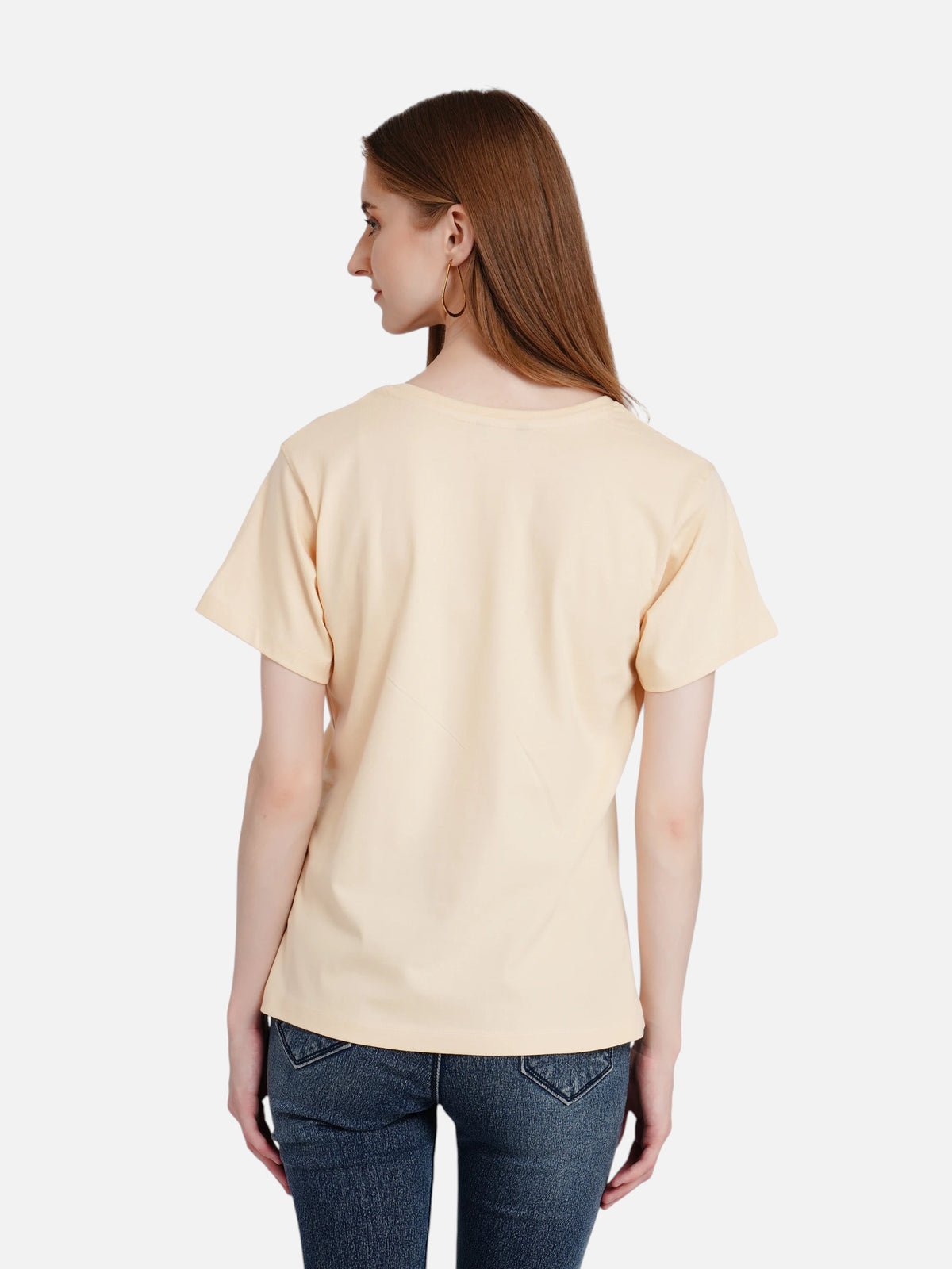 A model wearing an enaay.com beige crew-neck cotton t-shirt, viewed from the back, paired with blue denim jeans.