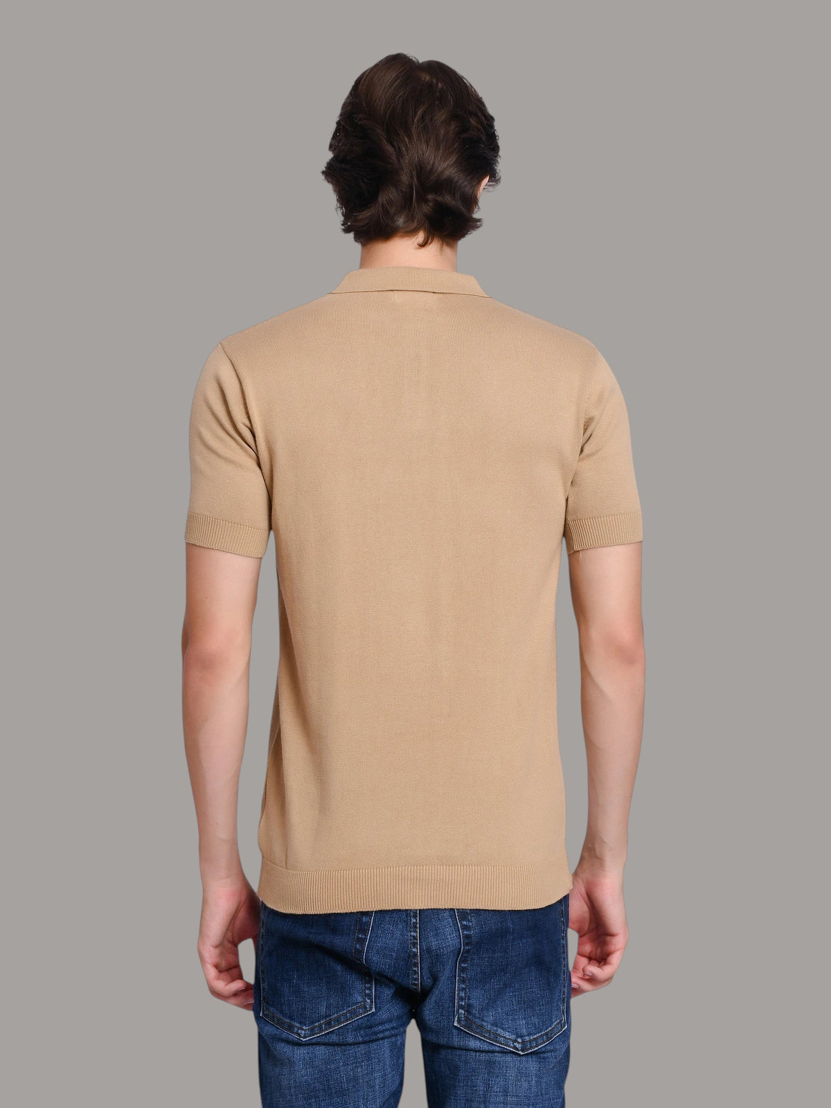 Back view of a man wearing an enaay.com beige knit polo shirt with short sleeves and ribbed hem, paired with jeans.