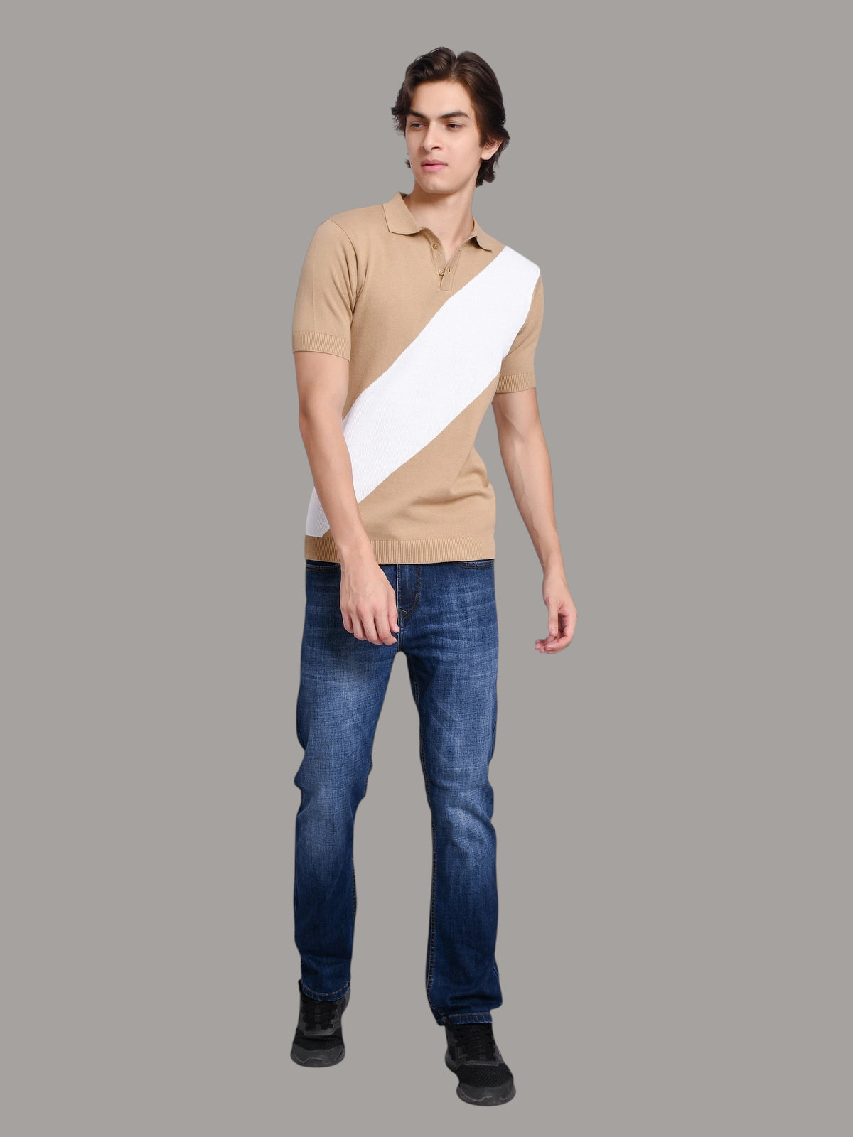 A model wearing an enaay.com beige and white diagonal stripe knit polo shirt with blue jeans against a grey background.