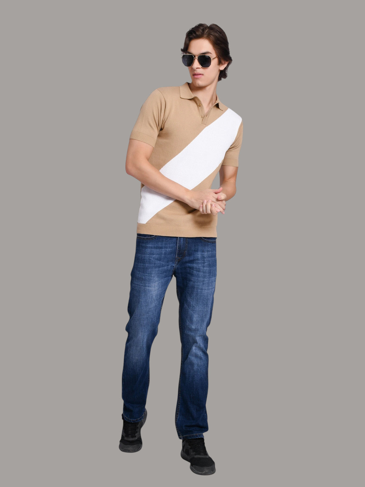 Model wearing an enaay.com beige and white diagonal stripe knit polo shirt with blue jeans and sunglasses.