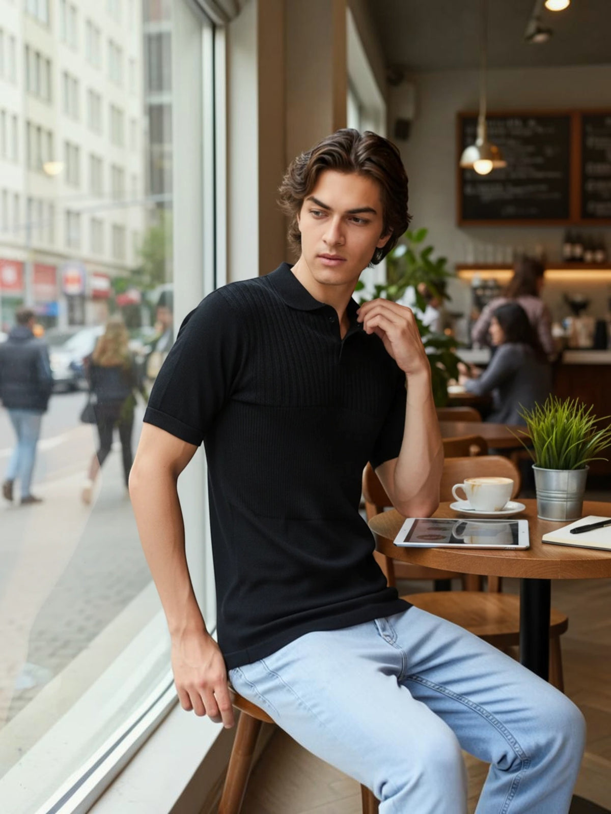 Man wearing an enaay.com black pure cotton knit polo shirt with a classic collar in a cafe setting.