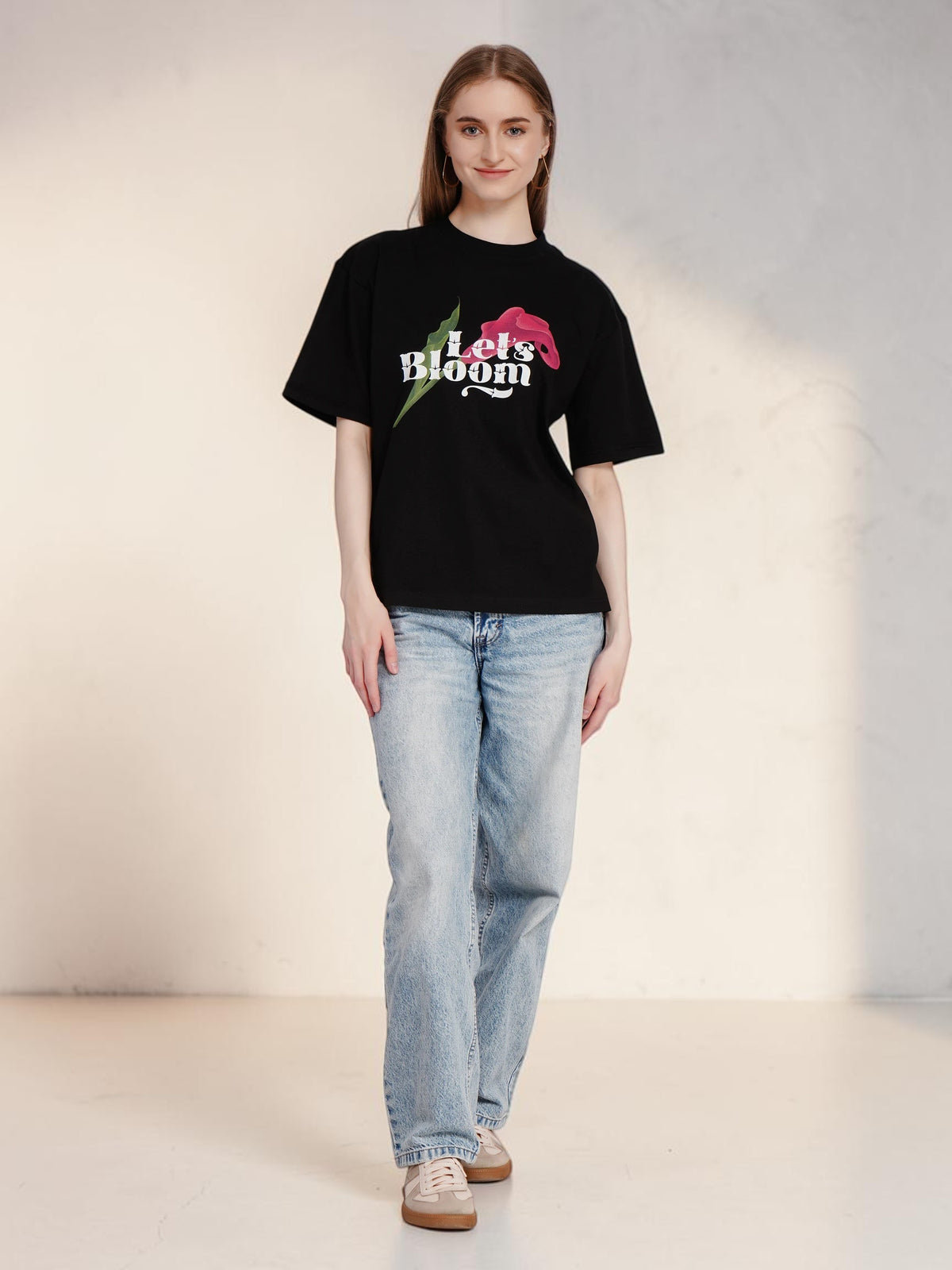 Model wearing an enaay.com black oversized cotton t-shirt with a Let's Bloom floral graphic print and round neck