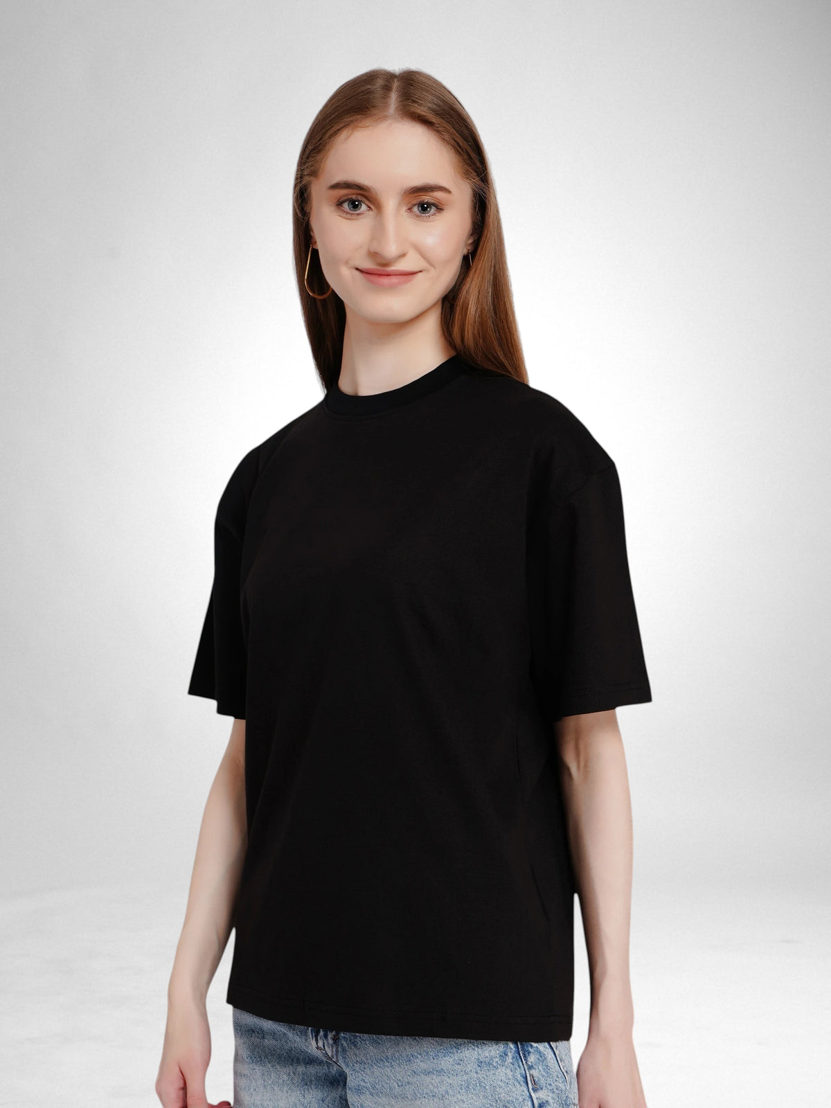 Woman wearing an enaay.com black oversized drop-shoulder t-shirt in premium 220 GSM cotton against a grey background