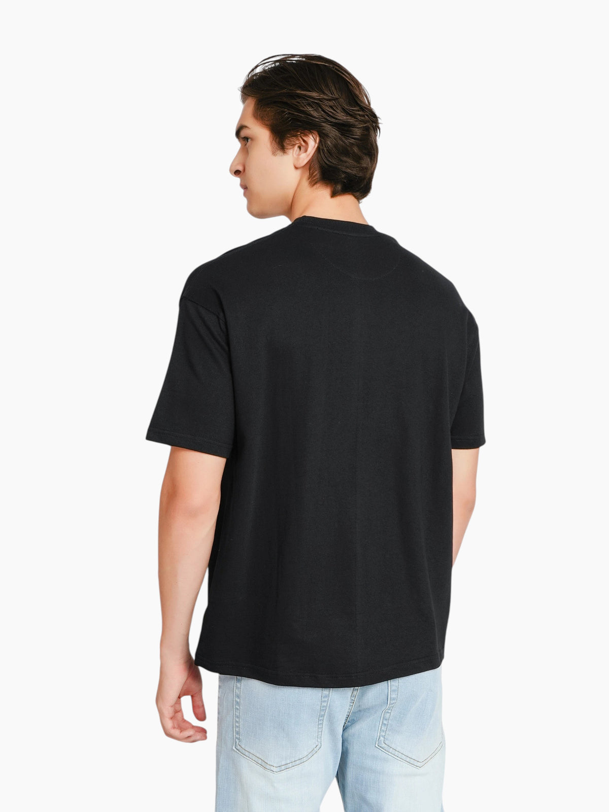 Back view of a man wearing an enaay.com black oversized crew-neck t-shirt with dropped shoulders and a boxy fit.