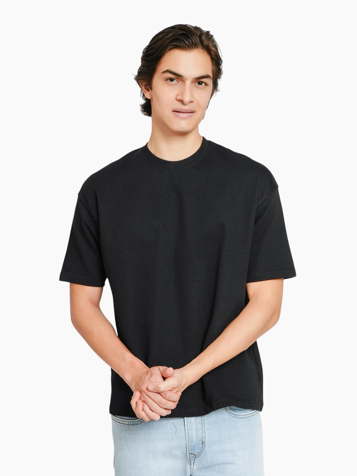 A man wearing an enaay.com black oversized crew-neck t-shirt with dropped shoulders and a relaxed fit.