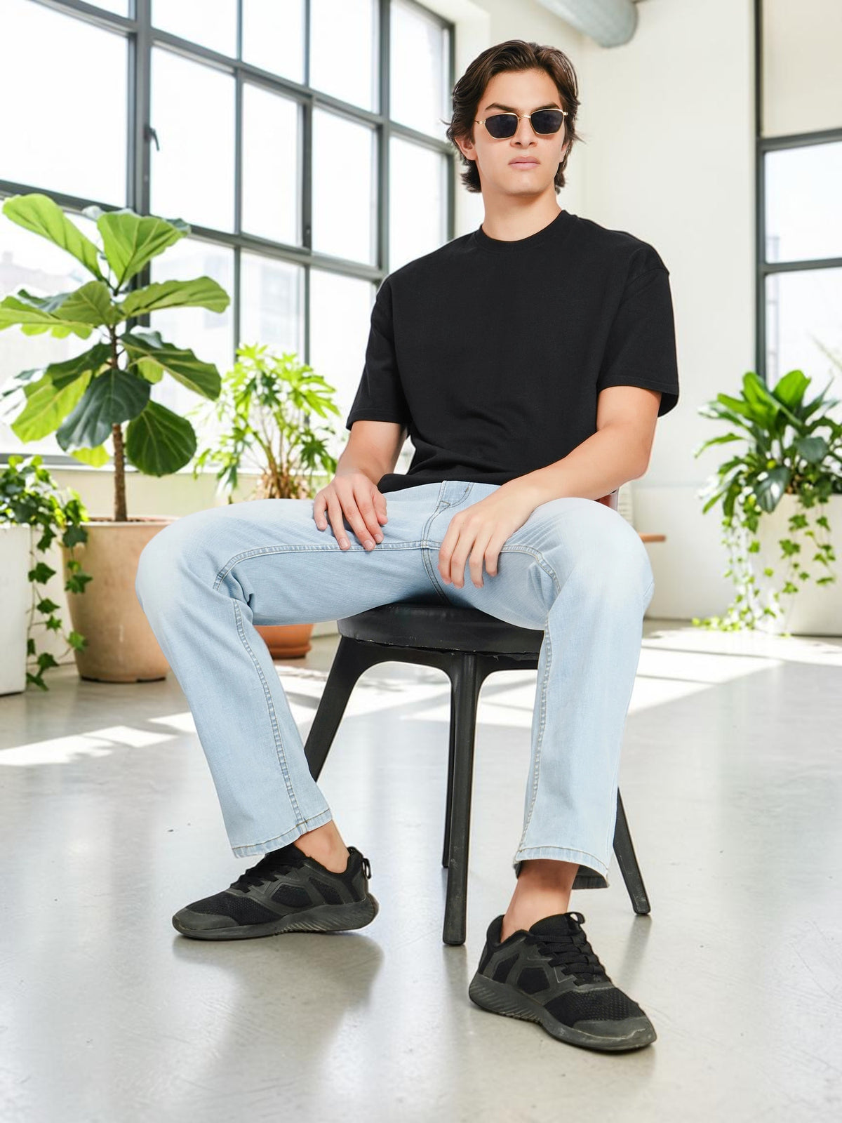 enaay.com men's black oversized crew-neck t-shirt worn by a model in a bright studio with light wash jeans.