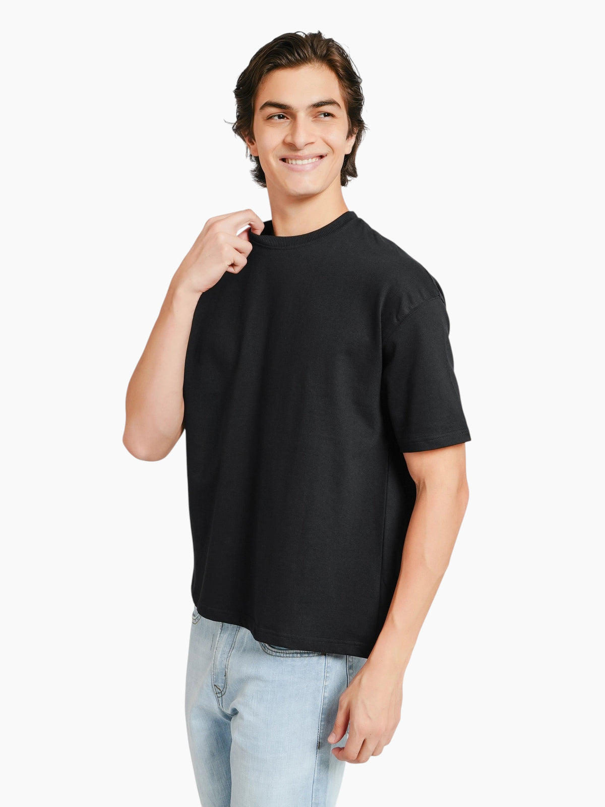 A man wearing an enaay.com black oversized crew-neck t-shirt with dropped shoulders and a boxy fit.