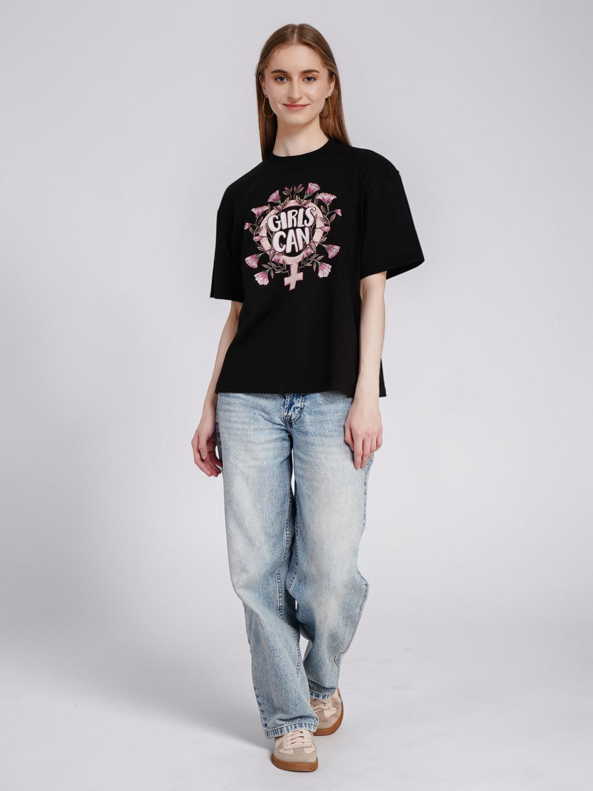 Model wearing an enaay.com black oversized cotton t-shirt with a Girls Can floral graphic print and light wash jeans.