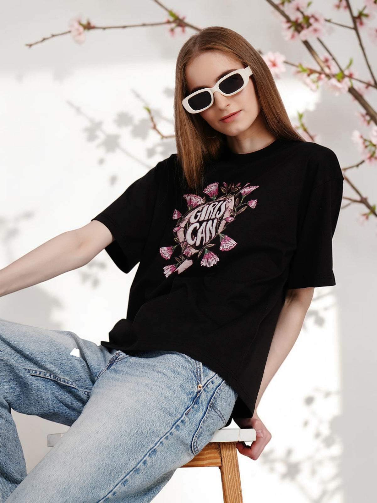 Model wearing an enaay.com black oversized cotton t-shirt with Girls Can graphic print and white sunglasses
