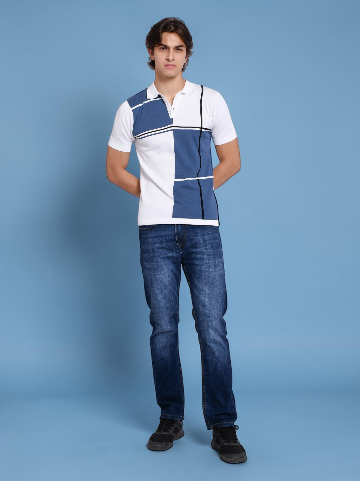 Model wearing an enaay.com blue and white color block knit polo shirt with black stripe accents and blue jeans.