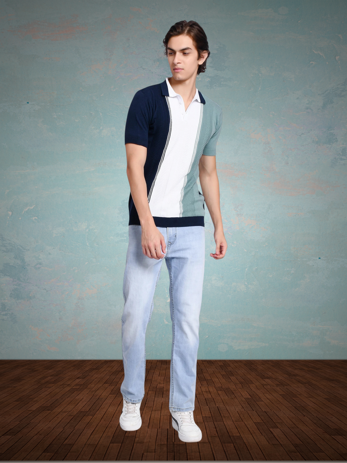Model wearing an enaay.com navy, white, and sage green colorblock knit polo shirt with vertical pinstripes and jeans