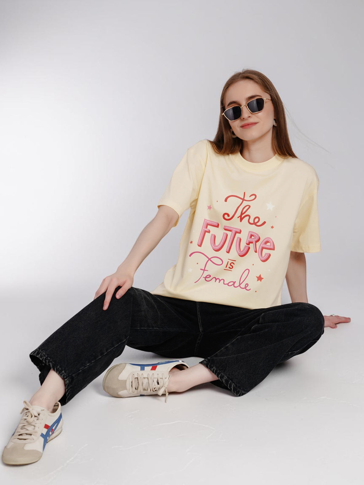 enaay.com light cream oversized cotton t-shirt with pink The Future Is Female graphic print worn by a seated model