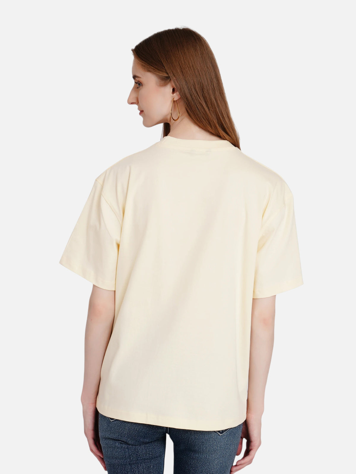 Back view of a woman wearing an enaay.com light cream loose fit cotton t-shirt with drop shoulders and round neck.