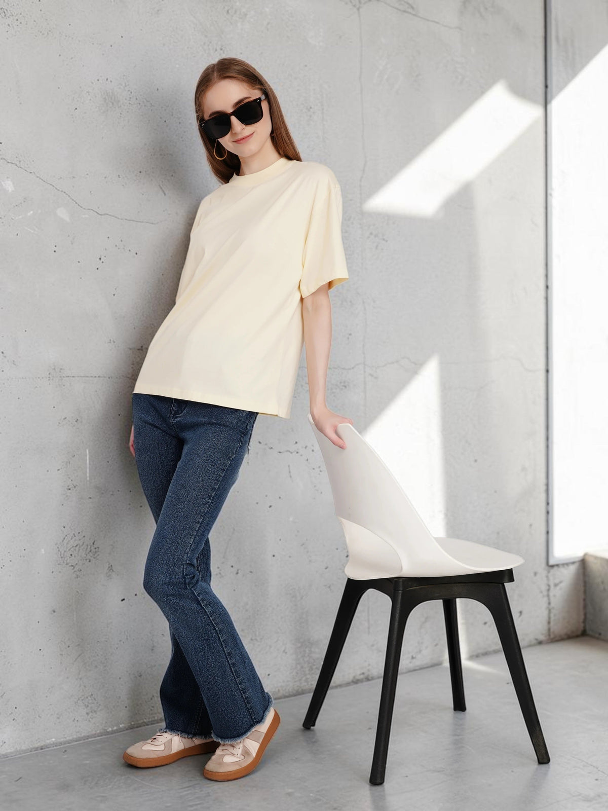 Model wearing an enaay.com light cream loose fit cotton t-shirt with drop shoulders and dark blue jeans