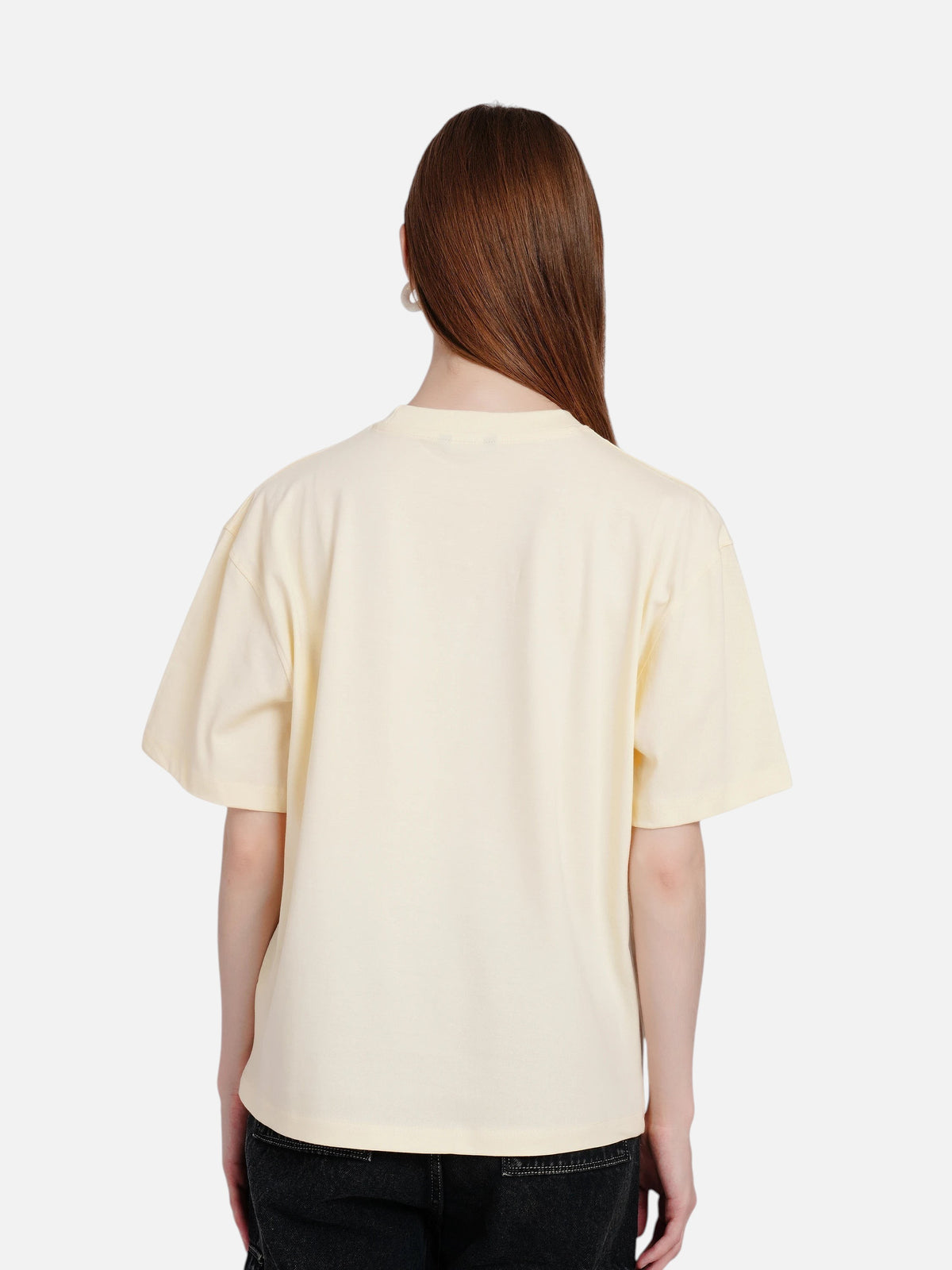 Back view of a woman wearing an enaay.com light cream oversized cotton t-shirt with drop shoulders