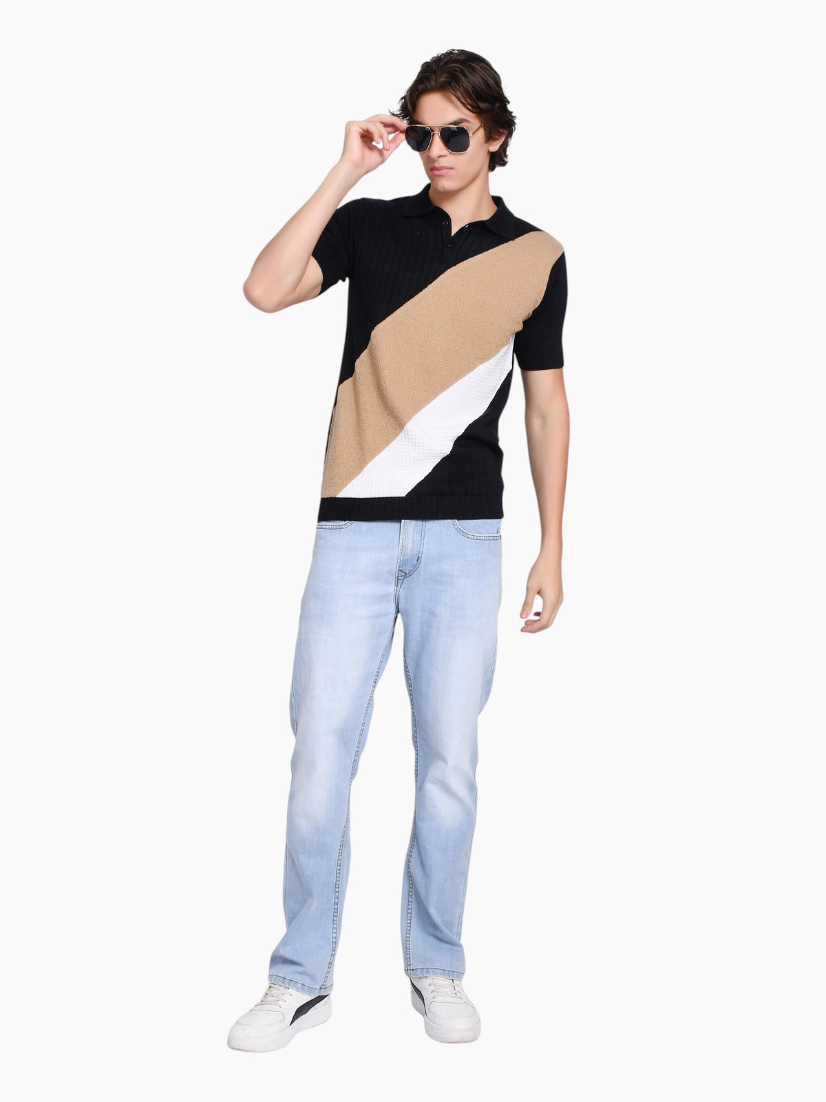 Model wearing an enaay.com black, beige, and white diagonal color-block knit polo shirt with light wash jeans.