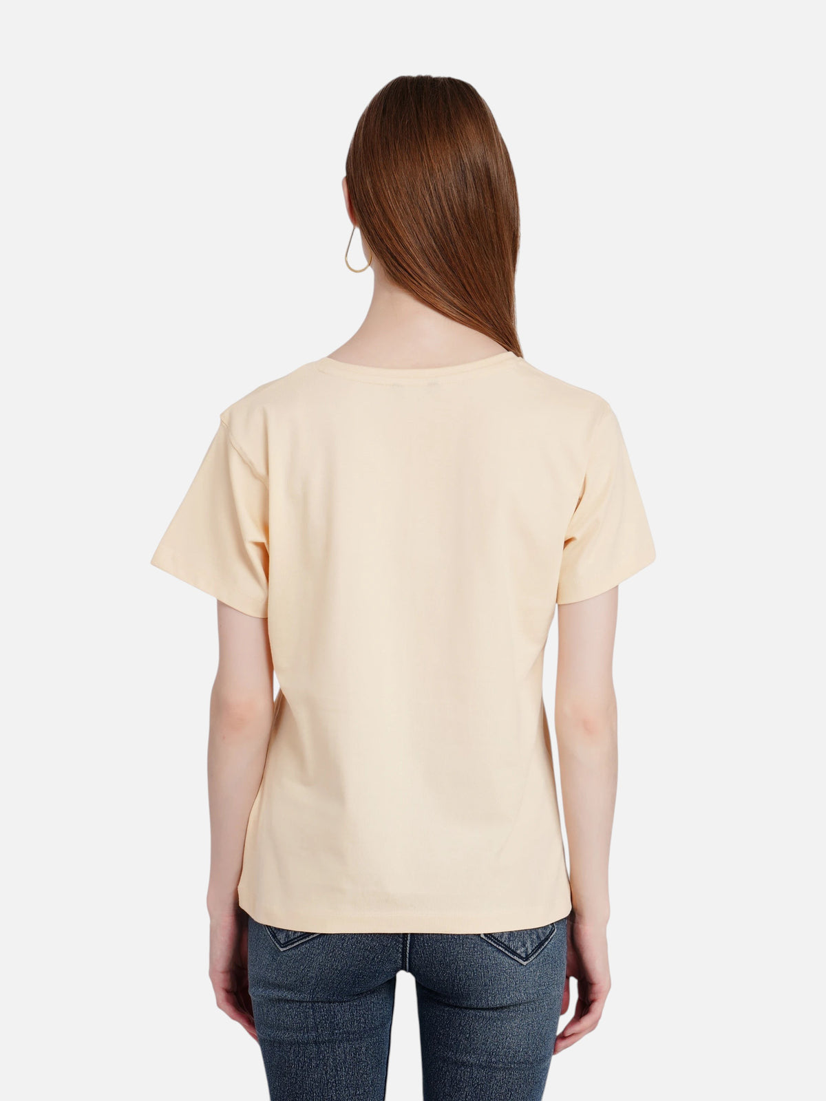 Back view of a woman wearing an enaay.com light beige cotton crew neck t-shirt with dark denim jeans