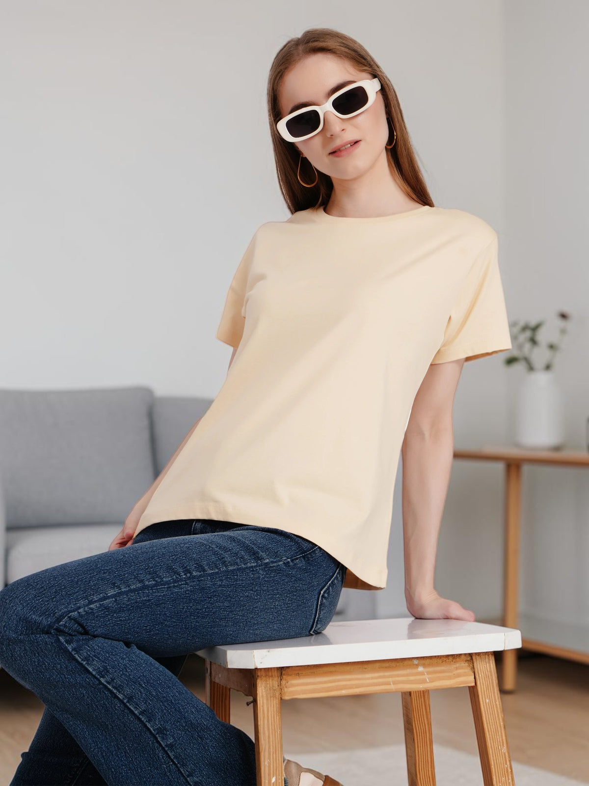 Model wearing an enaay.com light beige round neck cotton t-shirt with blue jeans and white sunglasses