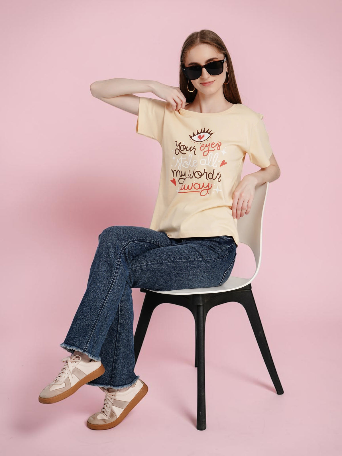 Model wearing enaay.com light beige cotton graphic t-shirt with eye and heart print, styled with jeans and sneakers.