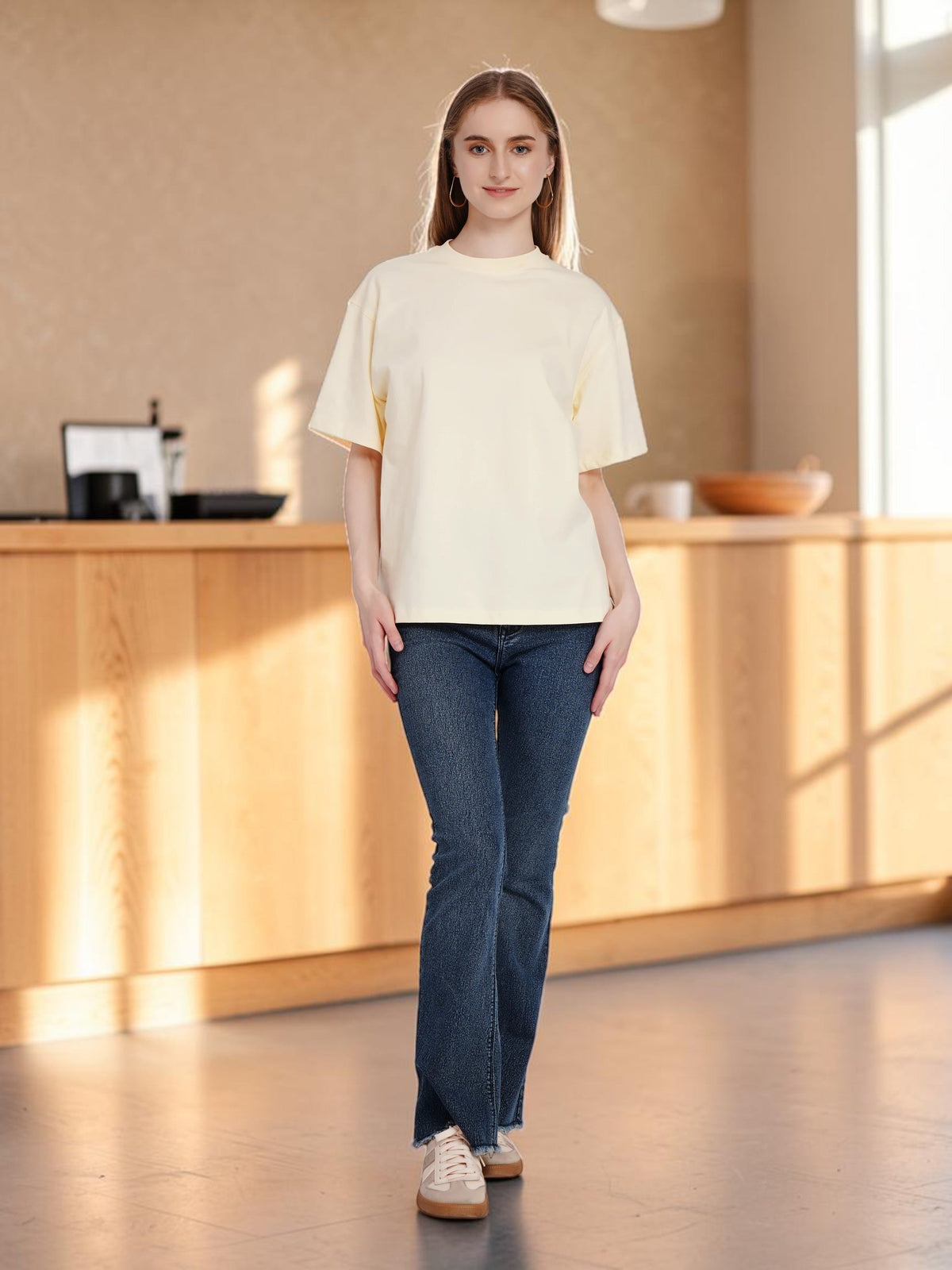 Model wearing an enaay.com light cream loose fit cotton t-shirt with drop shoulders and dark blue jeans