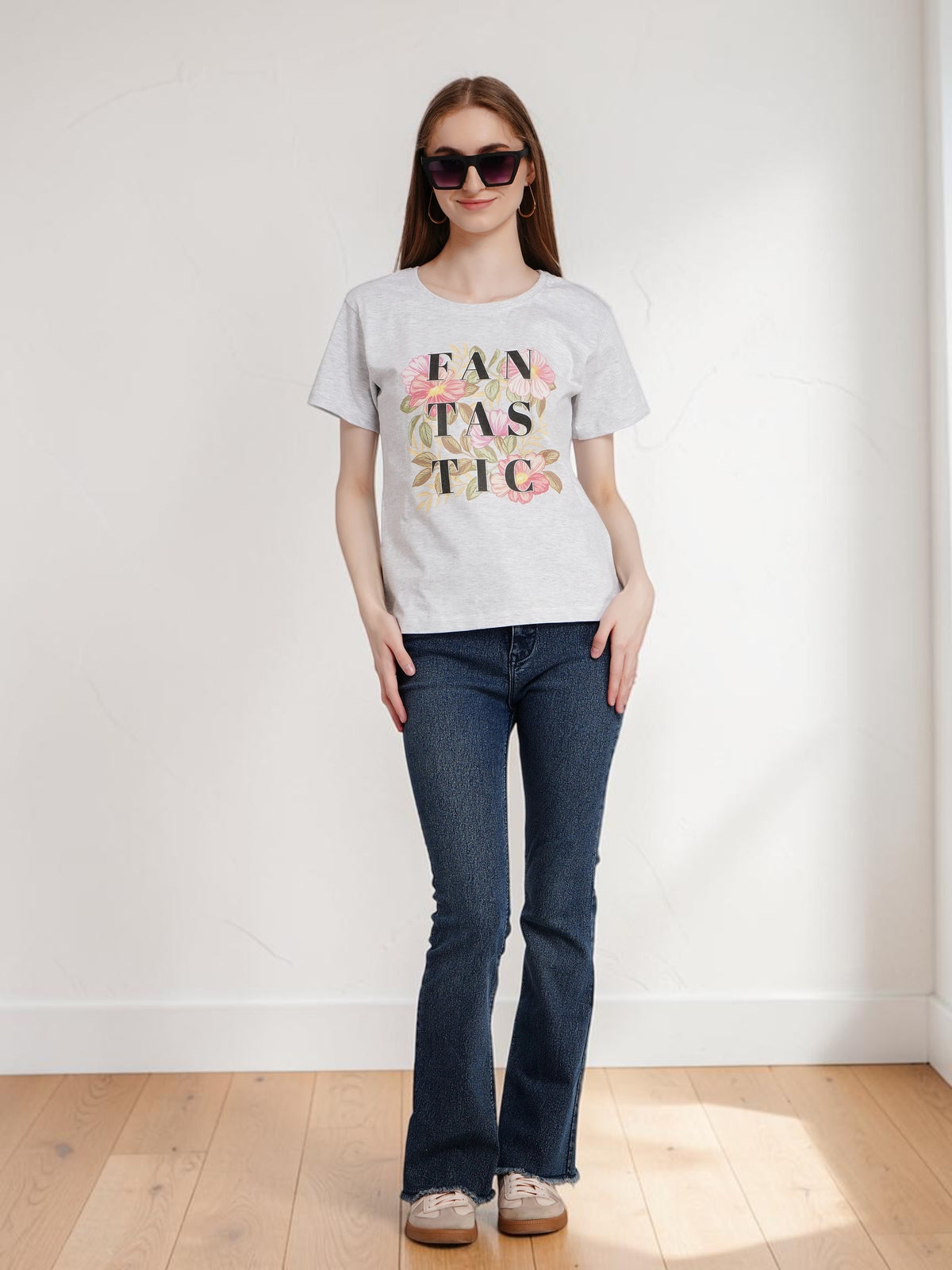 Model wearing an enaay.com light grey melange cotton t-shirt with a floral FANTASTIC graphic print and dark blue jeans