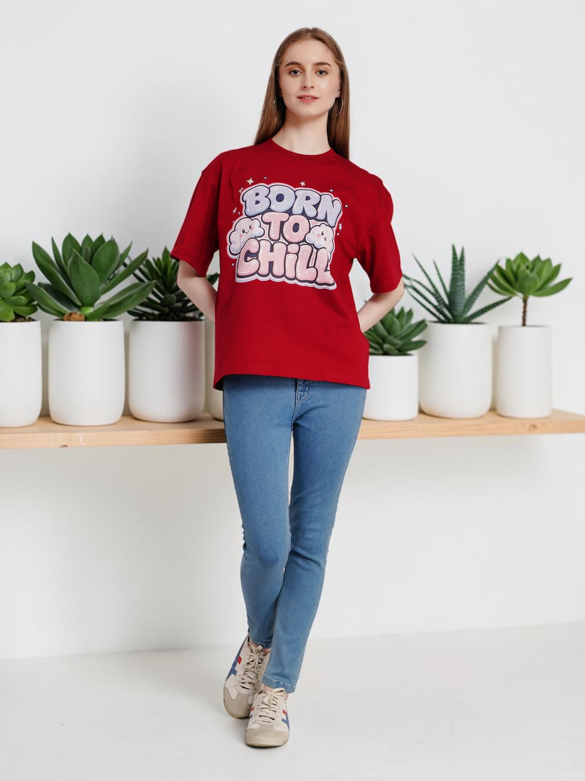 Model wearing an enaay.com maroon oversized cotton t-shirt with Born To Chill bubble letter graphic and cloud icons
