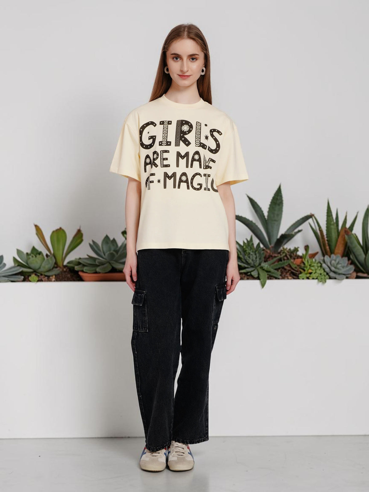 Model wearing an enaay.com off-white oversized cotton t-shirt with Girls Are Made Of Magic graphic and black cargo pants