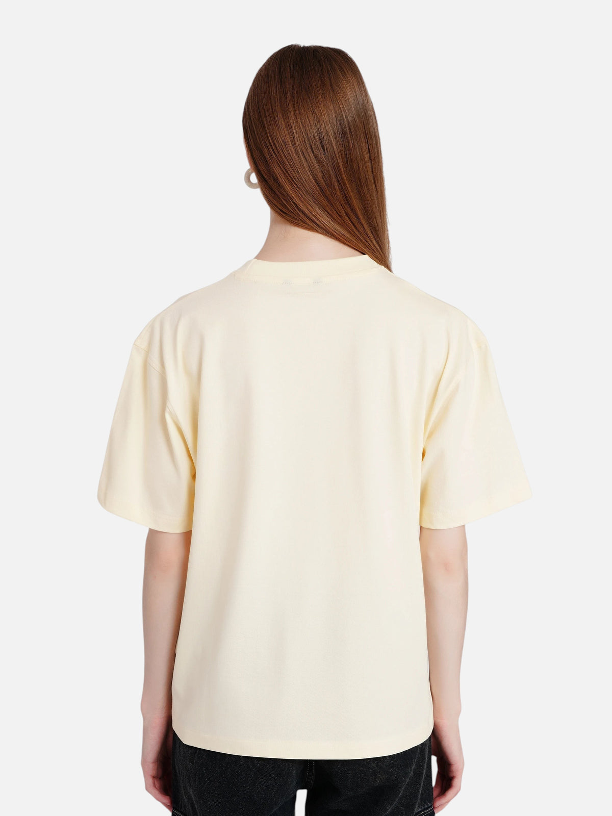Back view of a woman wearing an off-white oversized cotton t-shirt from enaay.com with a relaxed round neck.