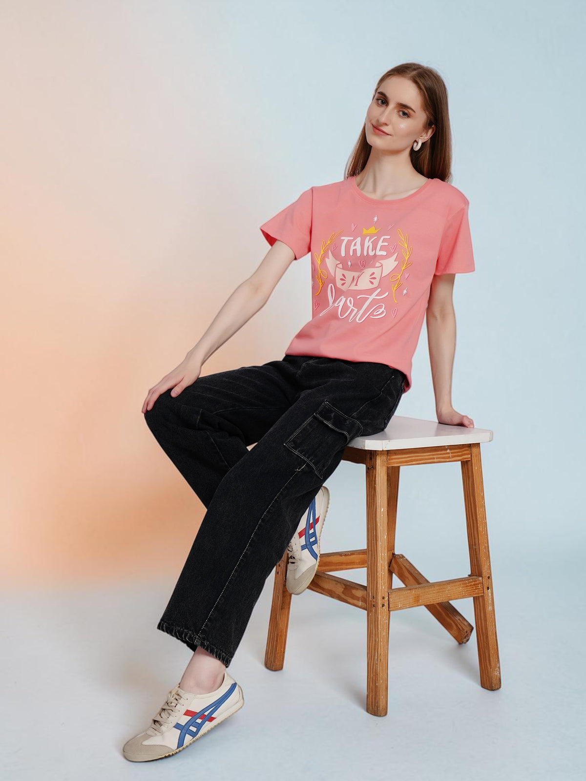 Model wearing an enaay.com coral pink cotton t-shirt with Take My Heart graphic print, black cargo pants, and sneakers.