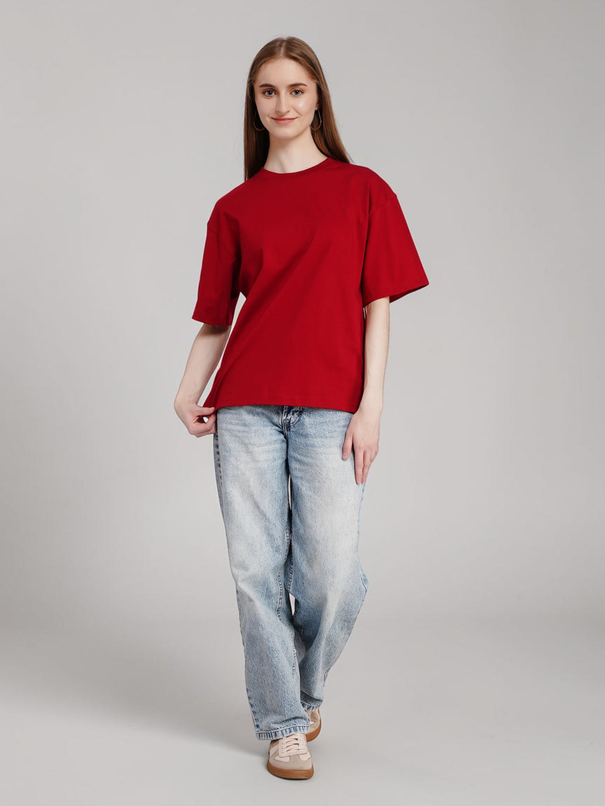 Model wearing an enaay.com red oversized premium cotton t-shirt with light wash jeans against a neutral background