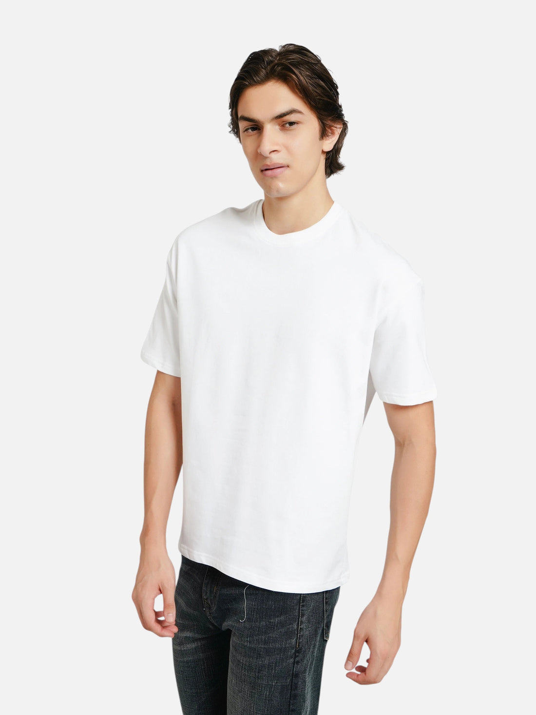 Model wearing an enaay.com white oversized crew-neck t-shirt with dropped shoulders and a boxy fit against a grey wall