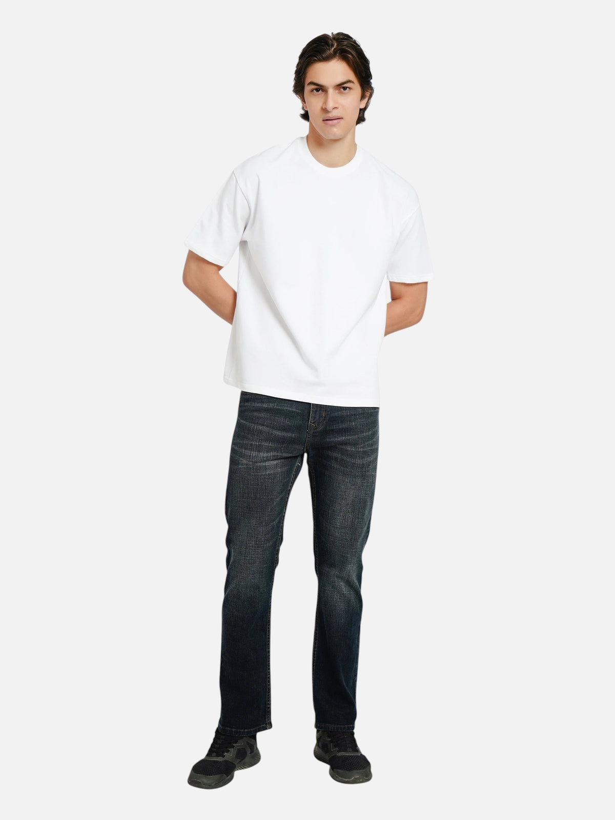 Model wearing an enaay.com white oversized crew-neck t-shirt with dropped shoulders and dark denim jeans