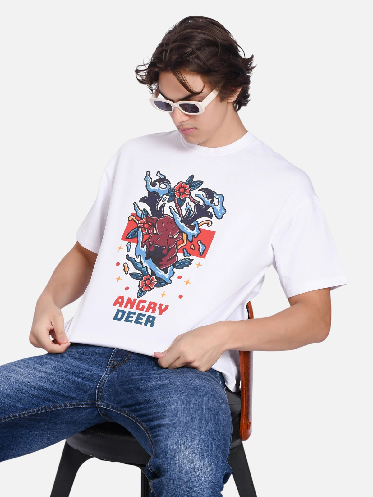 Model wearing an enaay.com white oversized t-shirt with a vibrant angry deer graphic print and white sunglasses