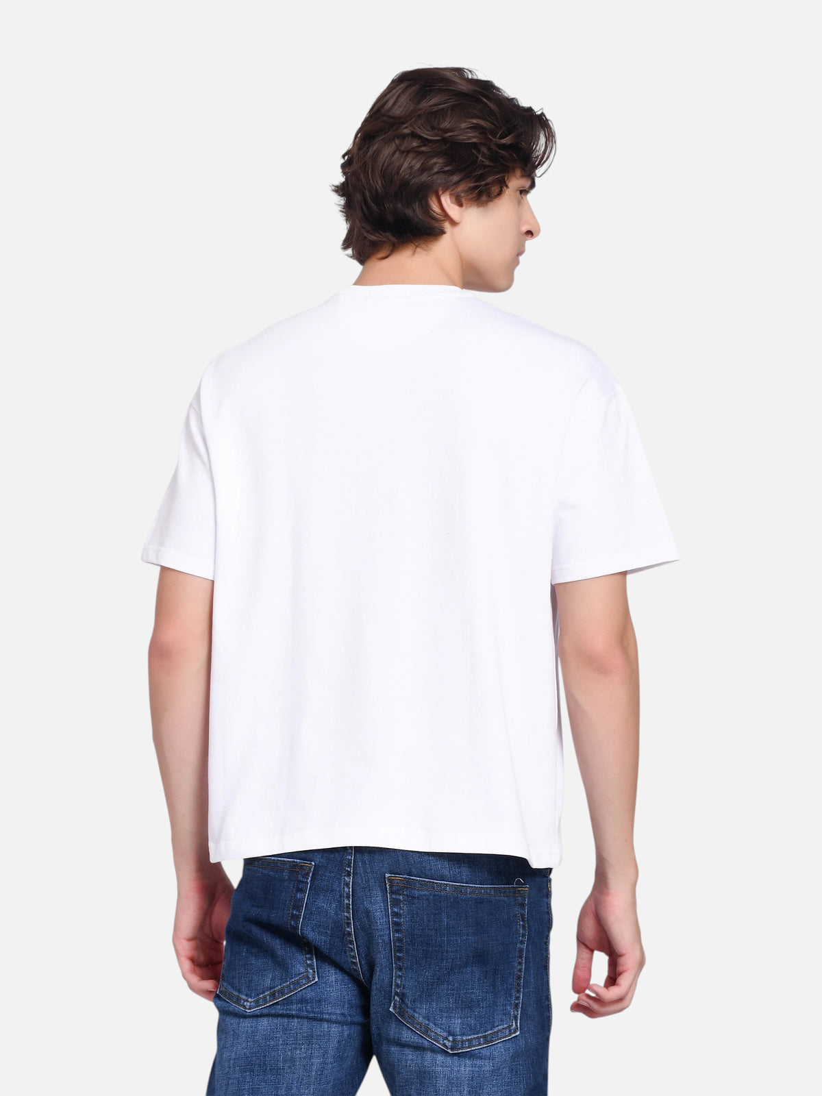 A man wearing an enaay.com white oversized t-shirt with a clean, plain back view, paired with blue denim jeans.